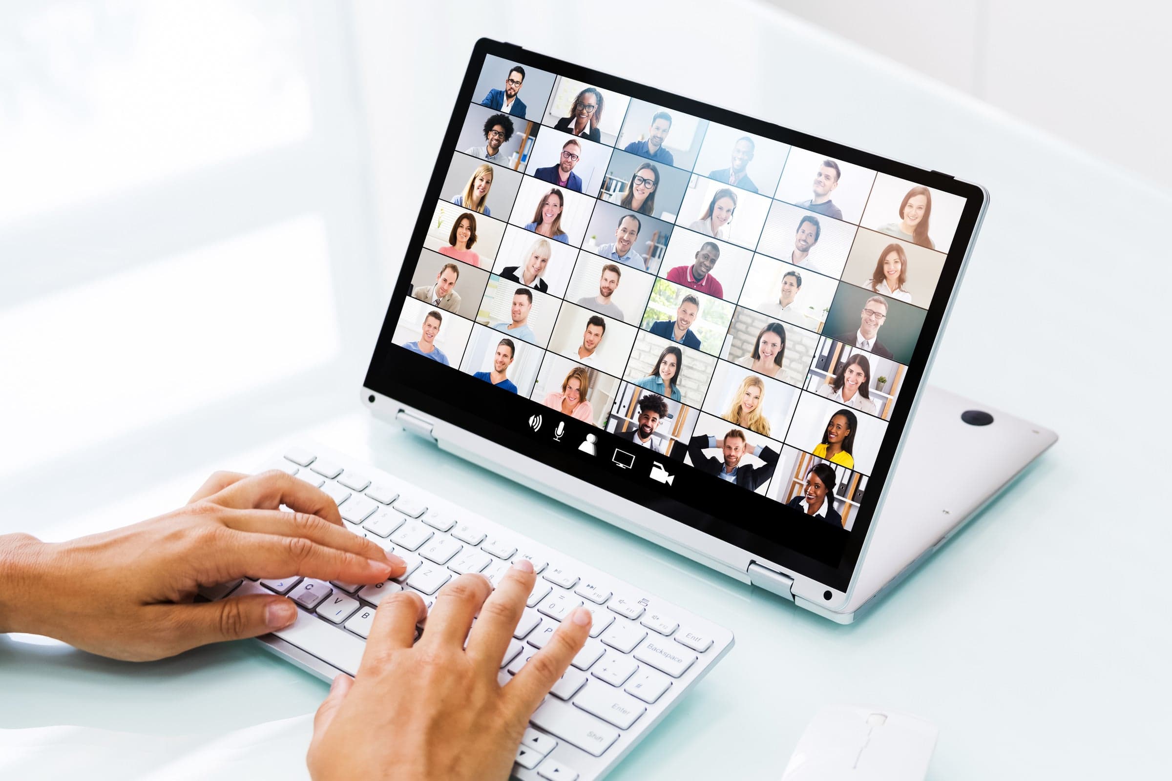 Laptop displaying a video call grid with a hand typing on the keyboard